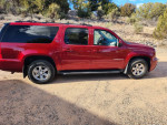 2013 GMC Yukon XL SLT in red, parked in a rural area, showcasing SUV features and style.