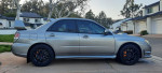 2007 Subaru Impreza WRX STI in silver with black wheels parked in a residential area