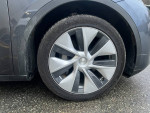 Close-up of a Tesla Model Y wheel showcasing its modern design and detail on a rainy day.