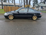Side view of a 1996 Honda Civic with gold wheels and a clean black exterior, parked in a residential area.