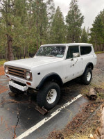 1972 International Scout in need of repair, showcasing solid body and broken front axle with forest background.