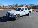 2005 Dodge Dakota SLT Quad Cab V8 parked in a lot, showcasing its white exterior and quad cab design.