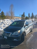 2006 Honda Odyssey in gray parked near snow with bright blue sky, ideal for family trips and outdoor adventures.