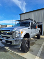 2016 Ford F250 Super Duty truck with a lift kit, aftermarket rims, and custom lumber rack.