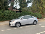 2017 Toyota Corolla L in excellent condition with new tires parked on the street surrounded by greenery