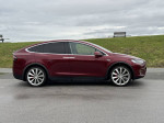 Side view of a 2016 Tesla Model X P90D in signature red, showcasing dual motor AWD and premium features.